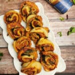 air fryer pillsbury pizza rolls on a white serving platter with pillsburry pizza crust package on the side.