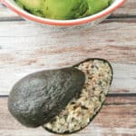avocado shell filled with rice krispie treats next to a salad bowl with avocado flesh.