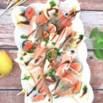 Fig and Pear Prosciutto Wraps in a white serving platter drizzled with balsamic glaze.