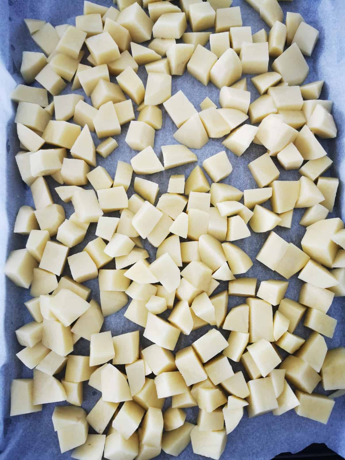 Peeled and cut Potato Cubes placed on parchment lined baking sheet