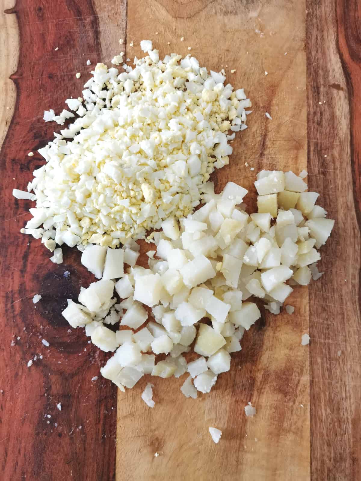 diced potatoes and chopped eggs on a cutting board.