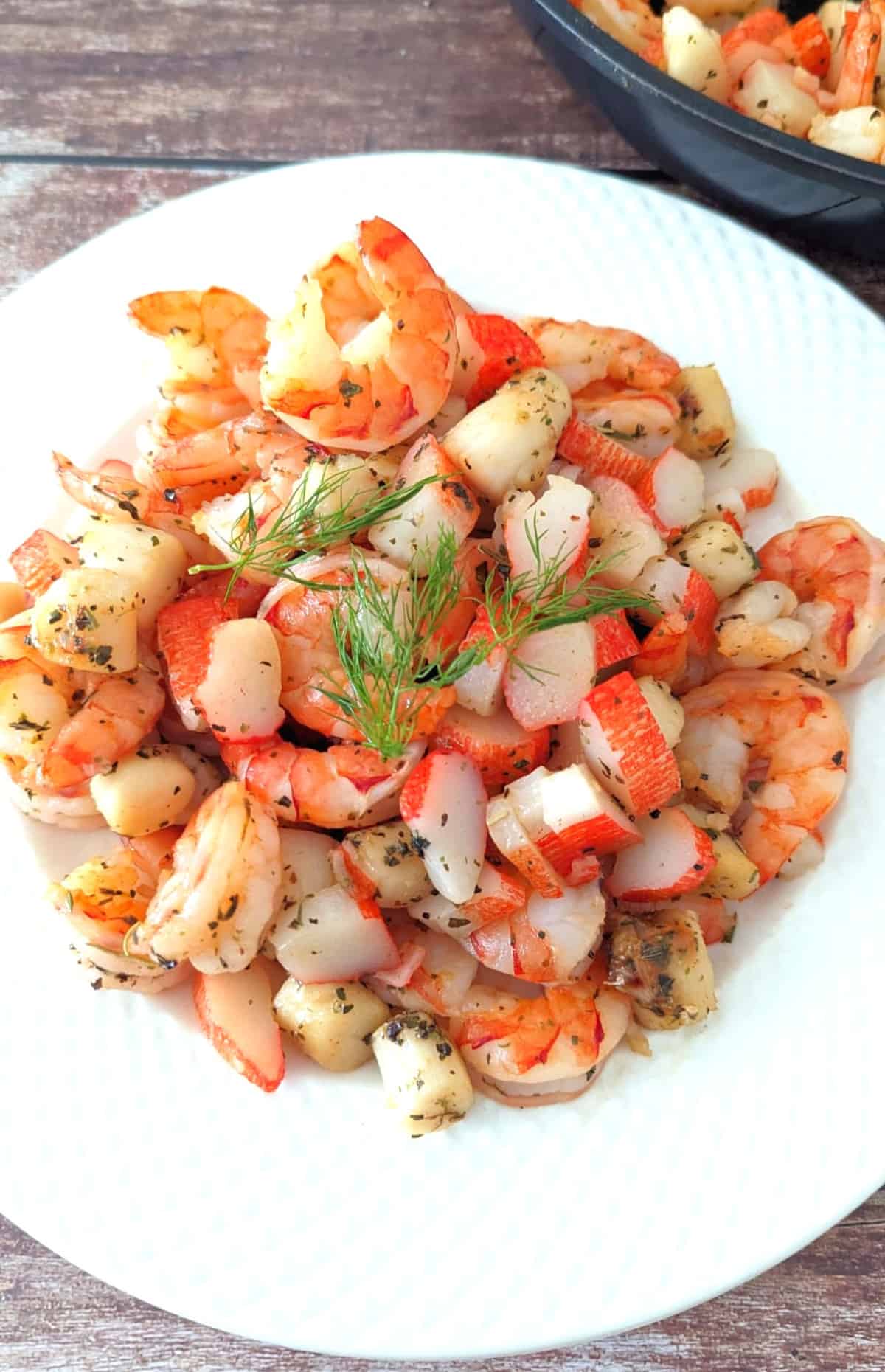 Sauteed Seafood Medley on white plate with pan on the side