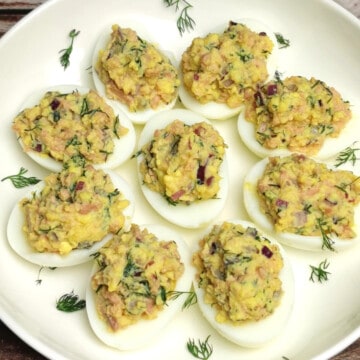 Cod Liver salad deviled eggs on a white plate with Brick background