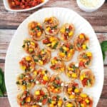 Sun-dried tomato and Mango Crostini ona white serving platter.