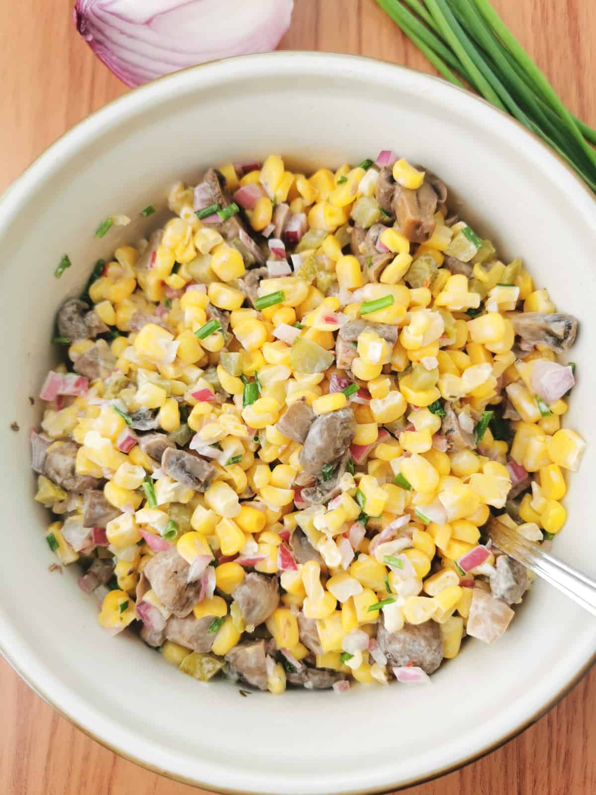 Corn and marinated mushroom salad in salad bowl with red onion and chives on the side