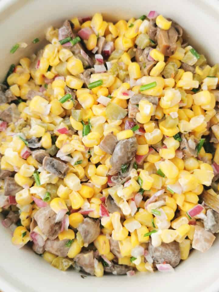 Corn and marinated mushroom salad in salad bowl with red onion and chives on the side