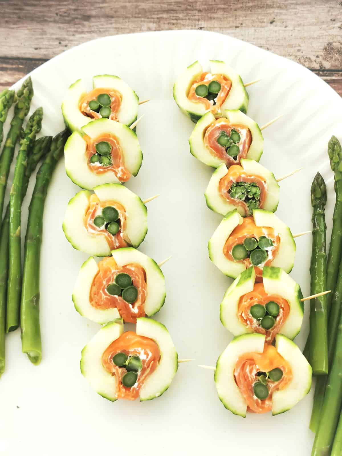 Asparagus in smoked salmon and cucumber appetizer on white serving platter