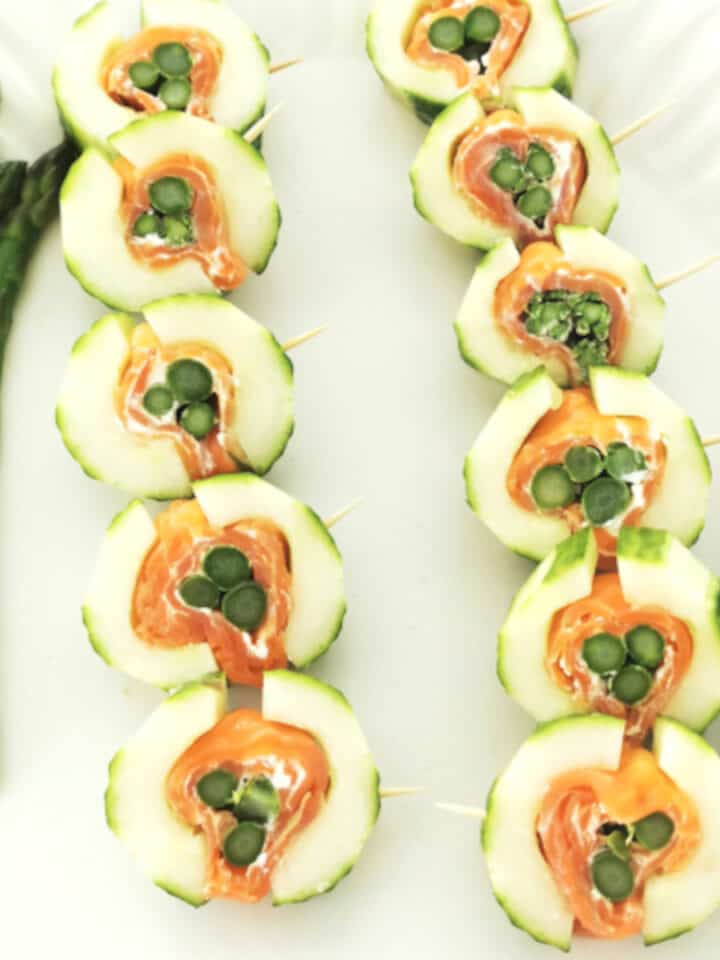 Asparagus in smoked salmon and cucumber appetizer on white serving platter.