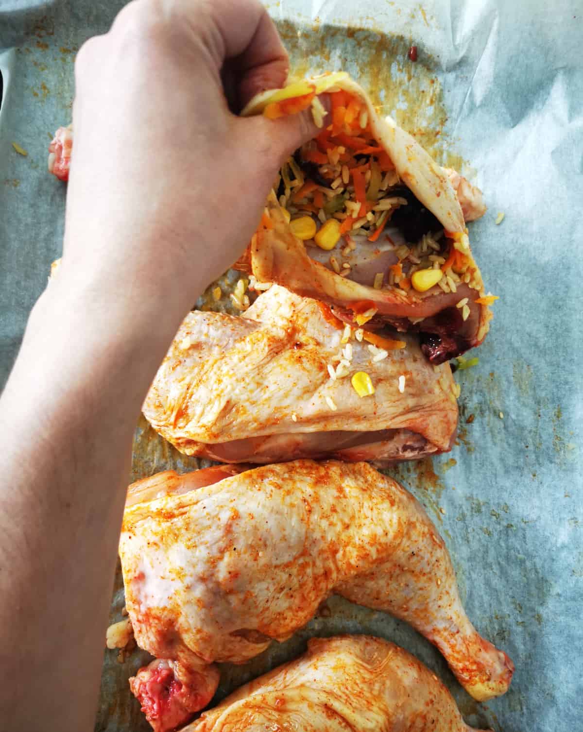 hand stuffing chicken quarters with sweet and savory rice mixture