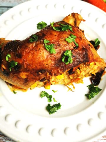 sweet and savory stuffed chicken quarters on white serving plate