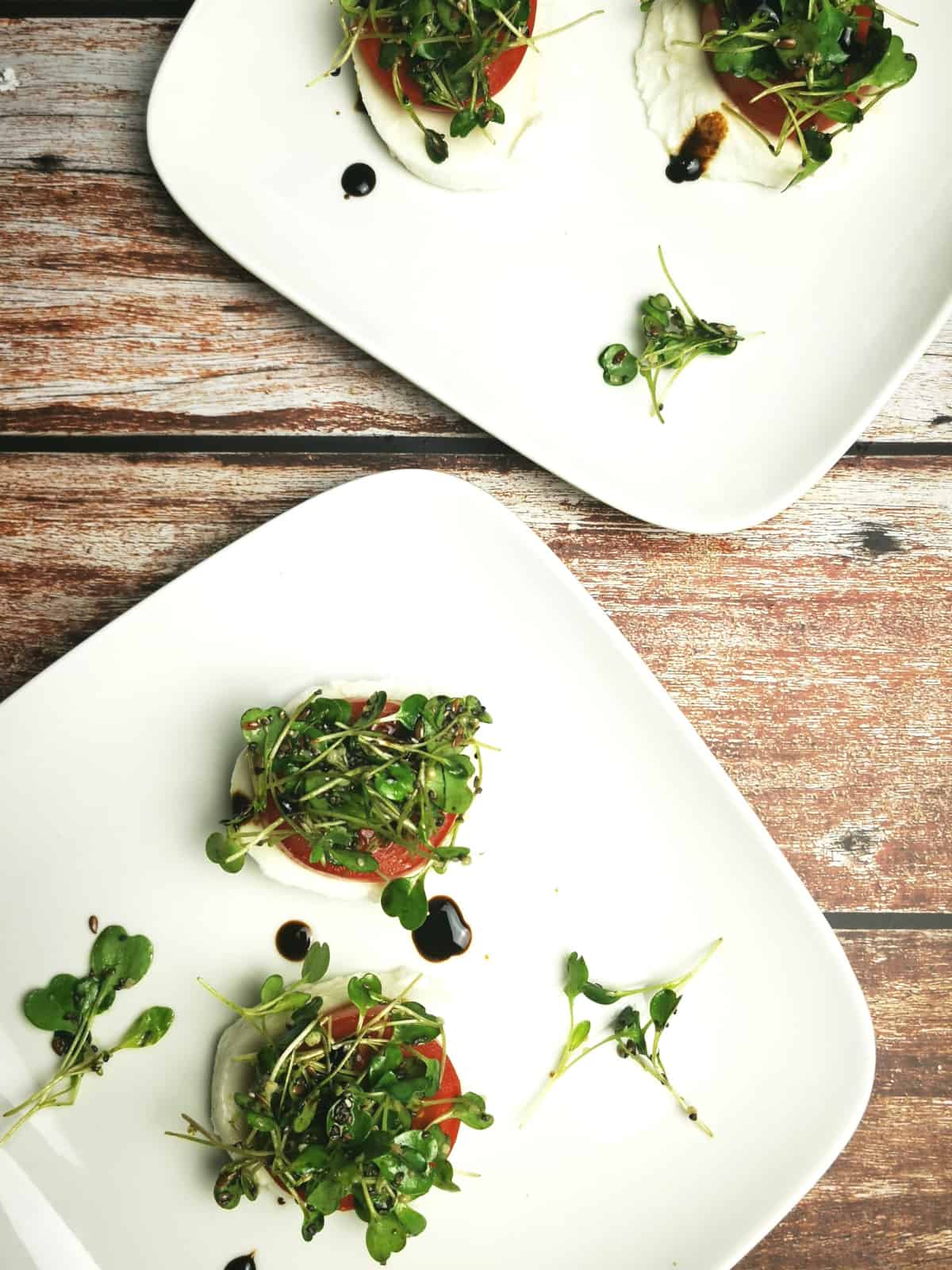 Caprese Salad with microgreens on a white serving platter