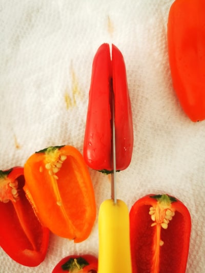 sharp knife cutting mini pepper in half lengthwise