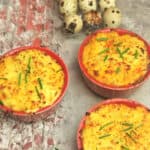 3 mini red bowls of shepherd's pie with quail eggs on the side.