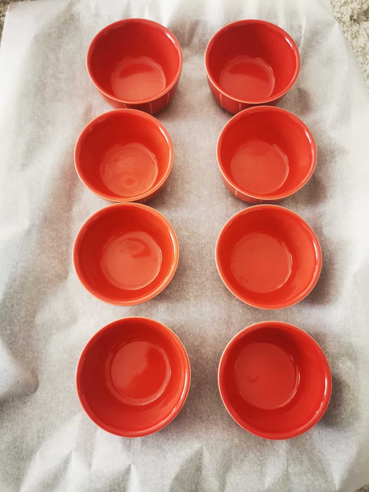 8 red bowls on parchment paper-lined baking dish