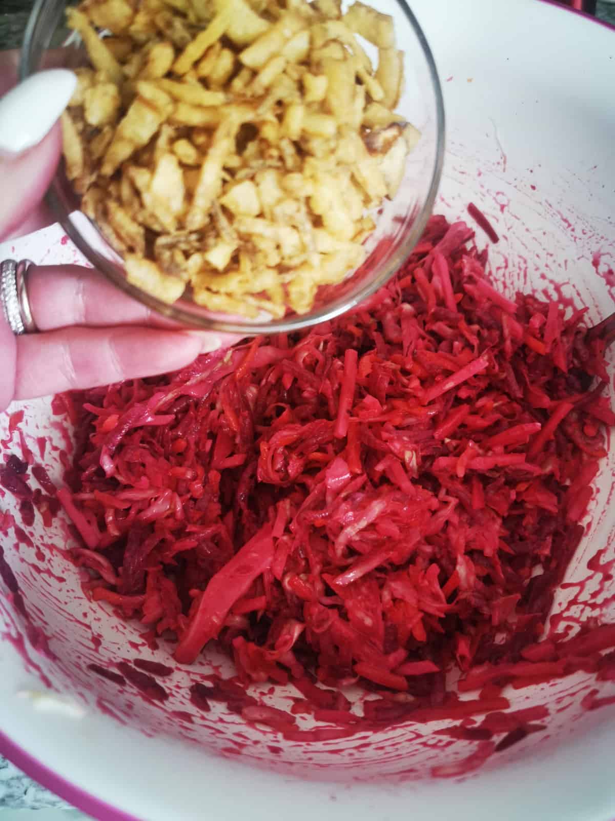 adding crispy onions into bowl with the sweet and crunchy beet salad