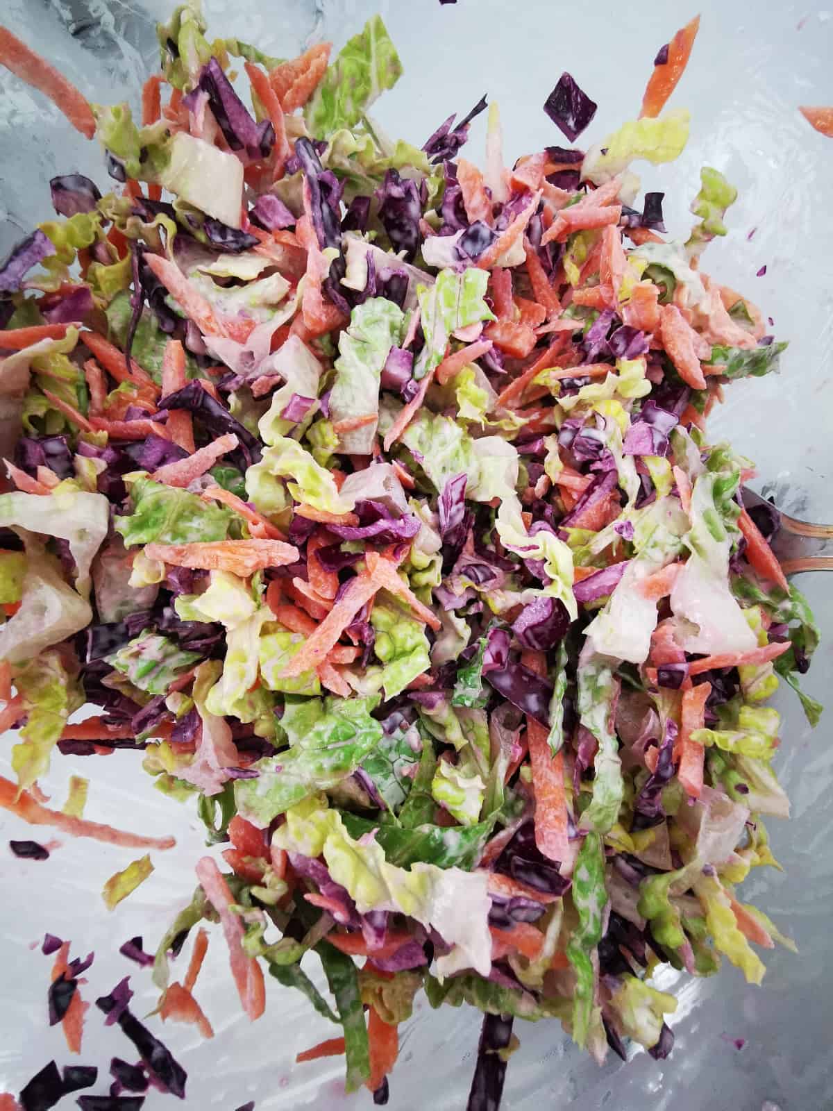 coleslaw inside a large glass mixing bowl.
