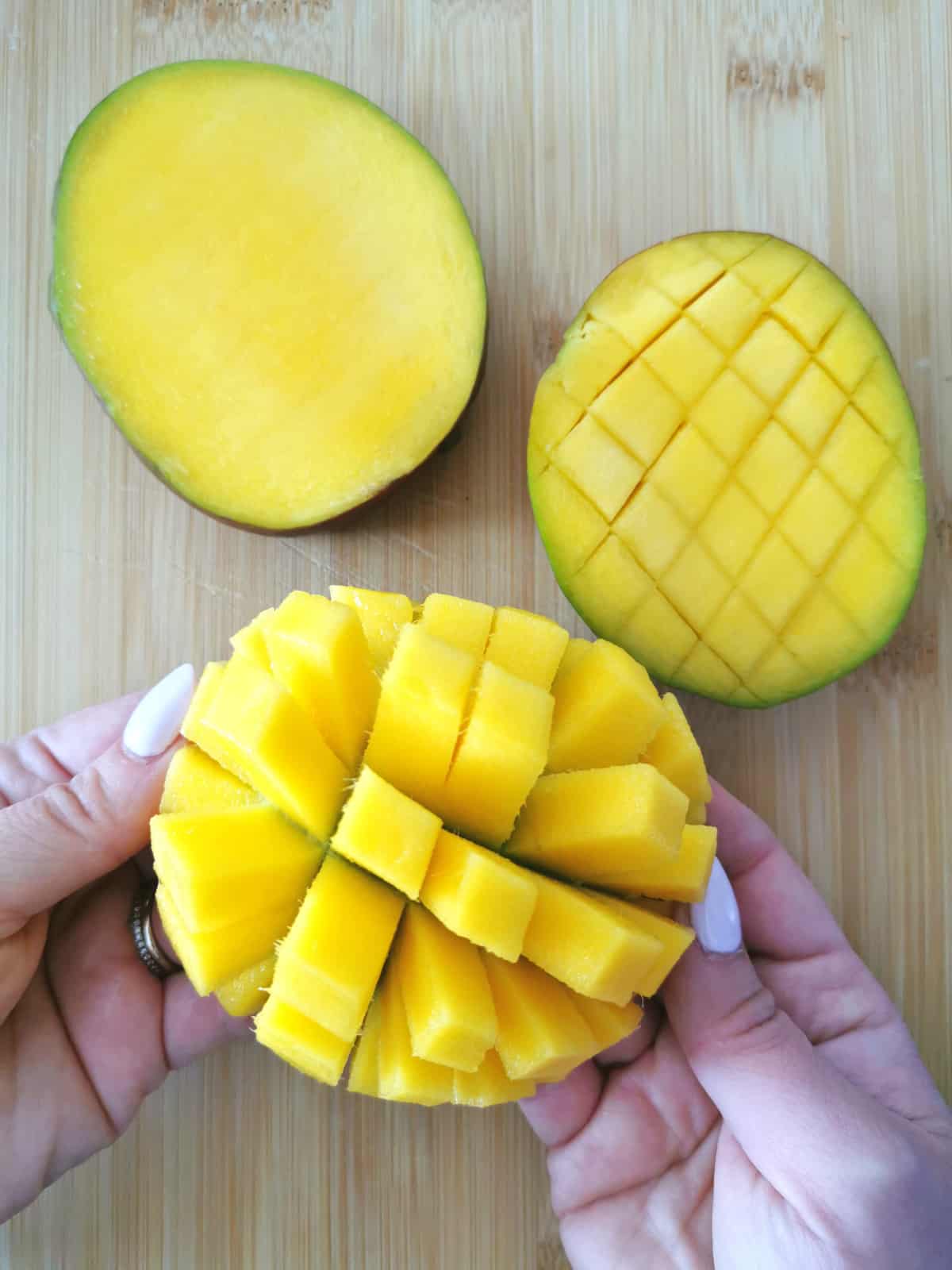 two hands inverting one mango cheek.