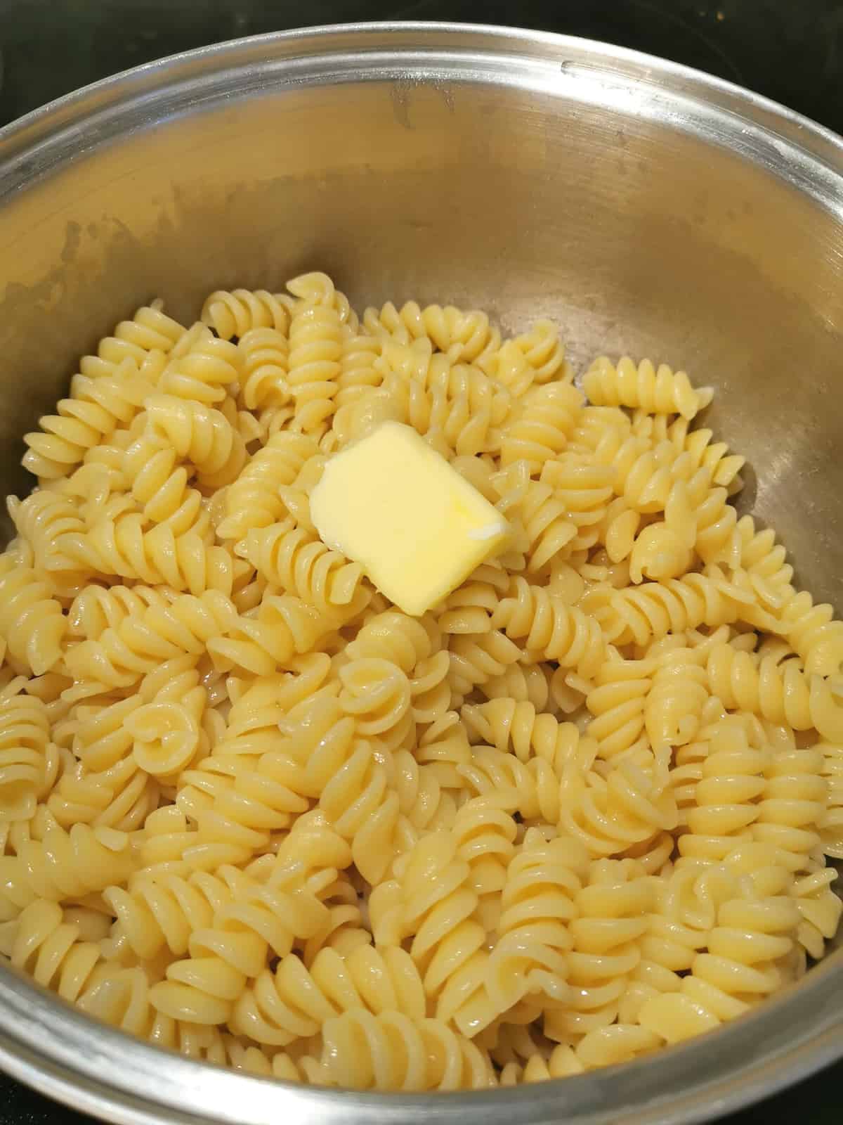 small piece of butter added to cooked pasta in a large pot.