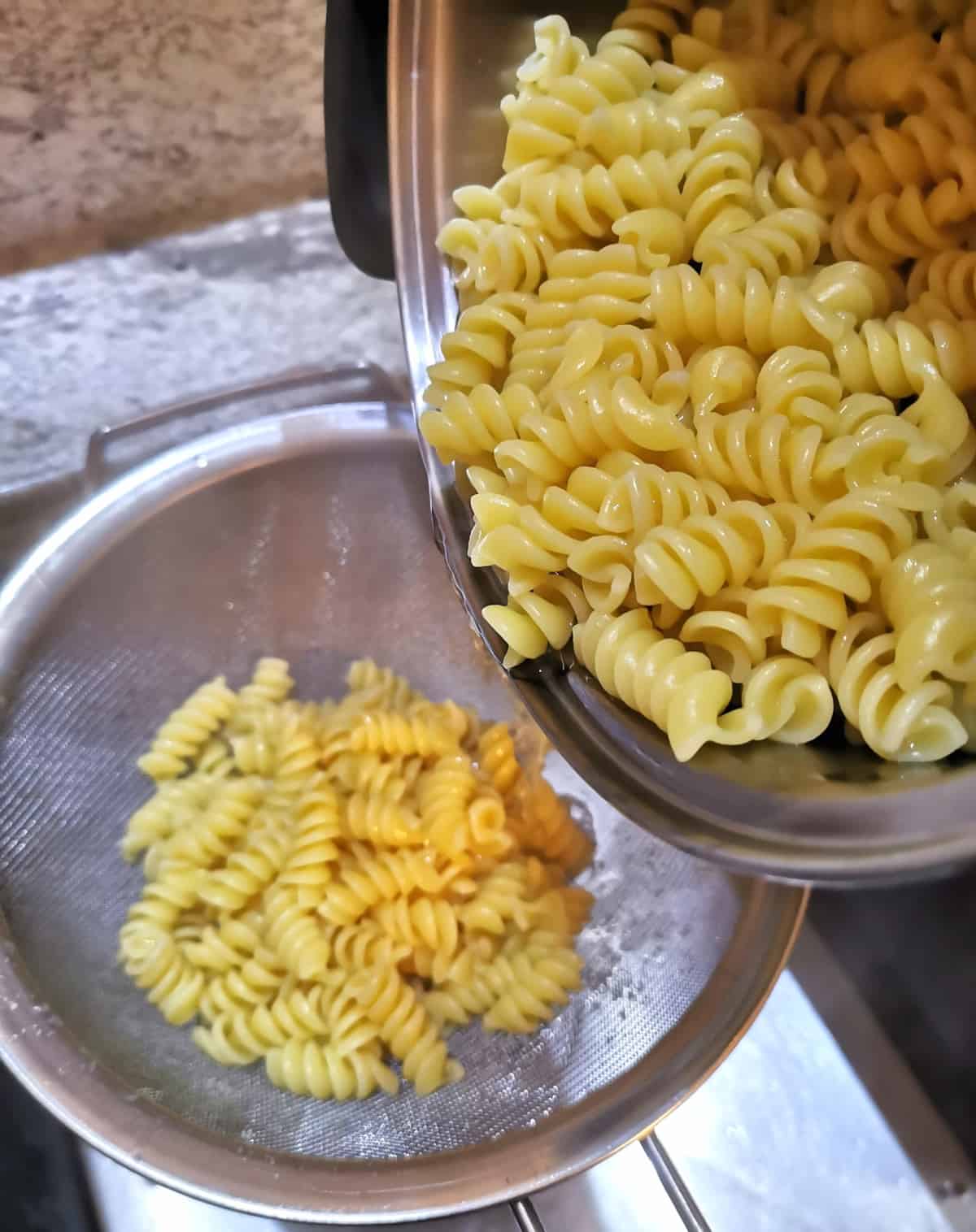 cooked pasta drained inside a colander in the sink.