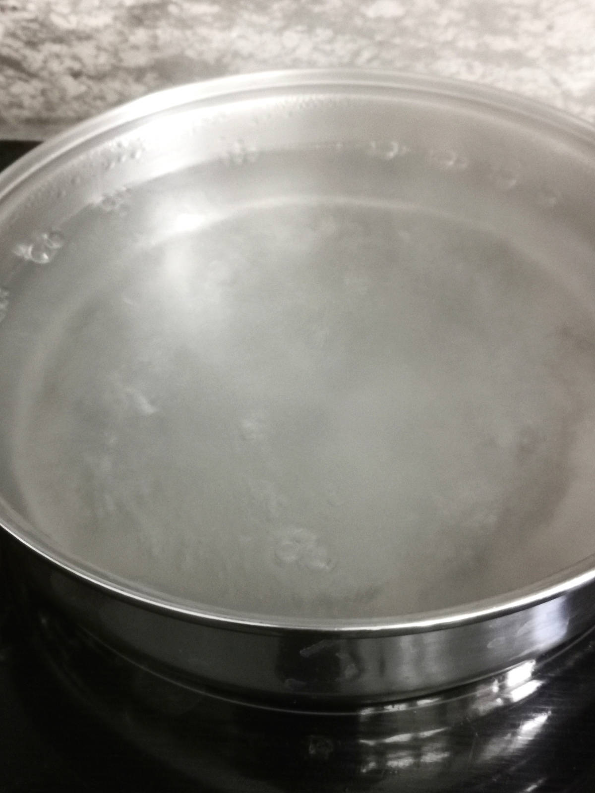water boiling in a large pot on the stove.