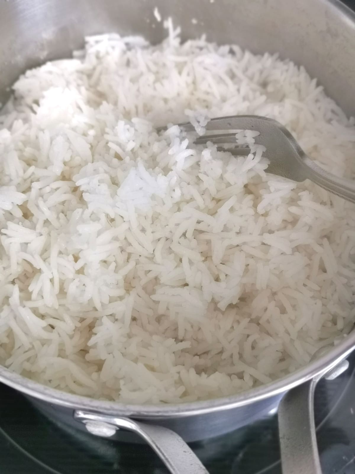 cooked rice in a pot fluffed with a fork.