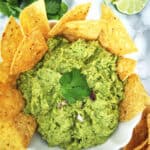 Quick Blender Guacamole in a white serving plate with tortilla chips.