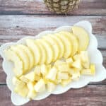 cut up pineapple in a white platter.