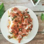 Cauliflower Steak with Prosciutto and Burrata on a small white plate.