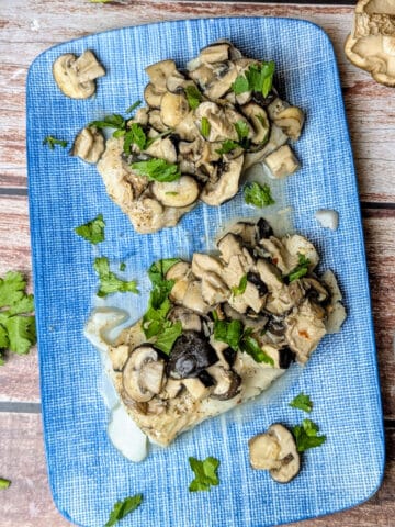 Baked Cod with Mushroom Sauce in Parchment Paper on blue platter.