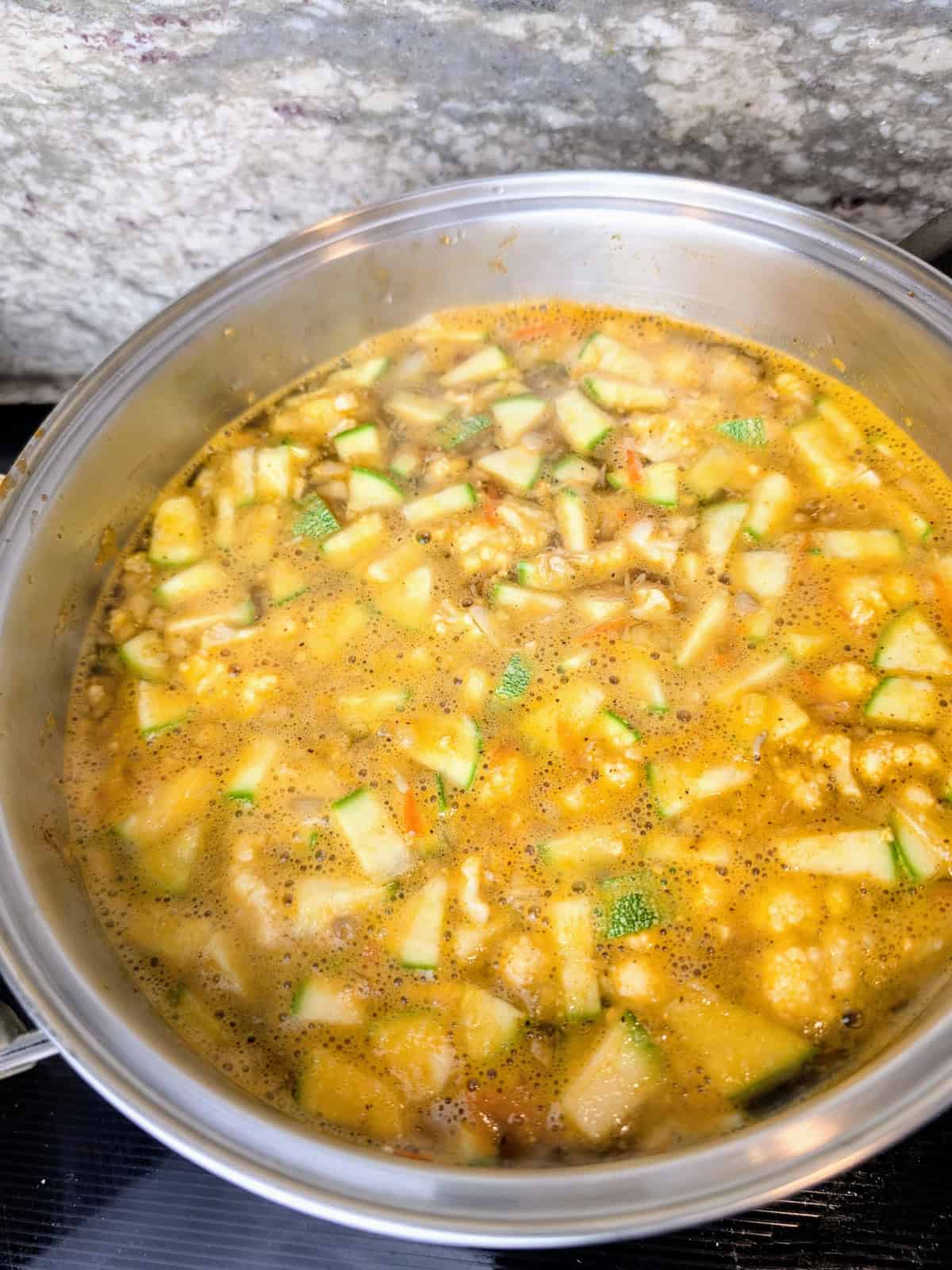 water added to vegetables cooking in pot on stove.