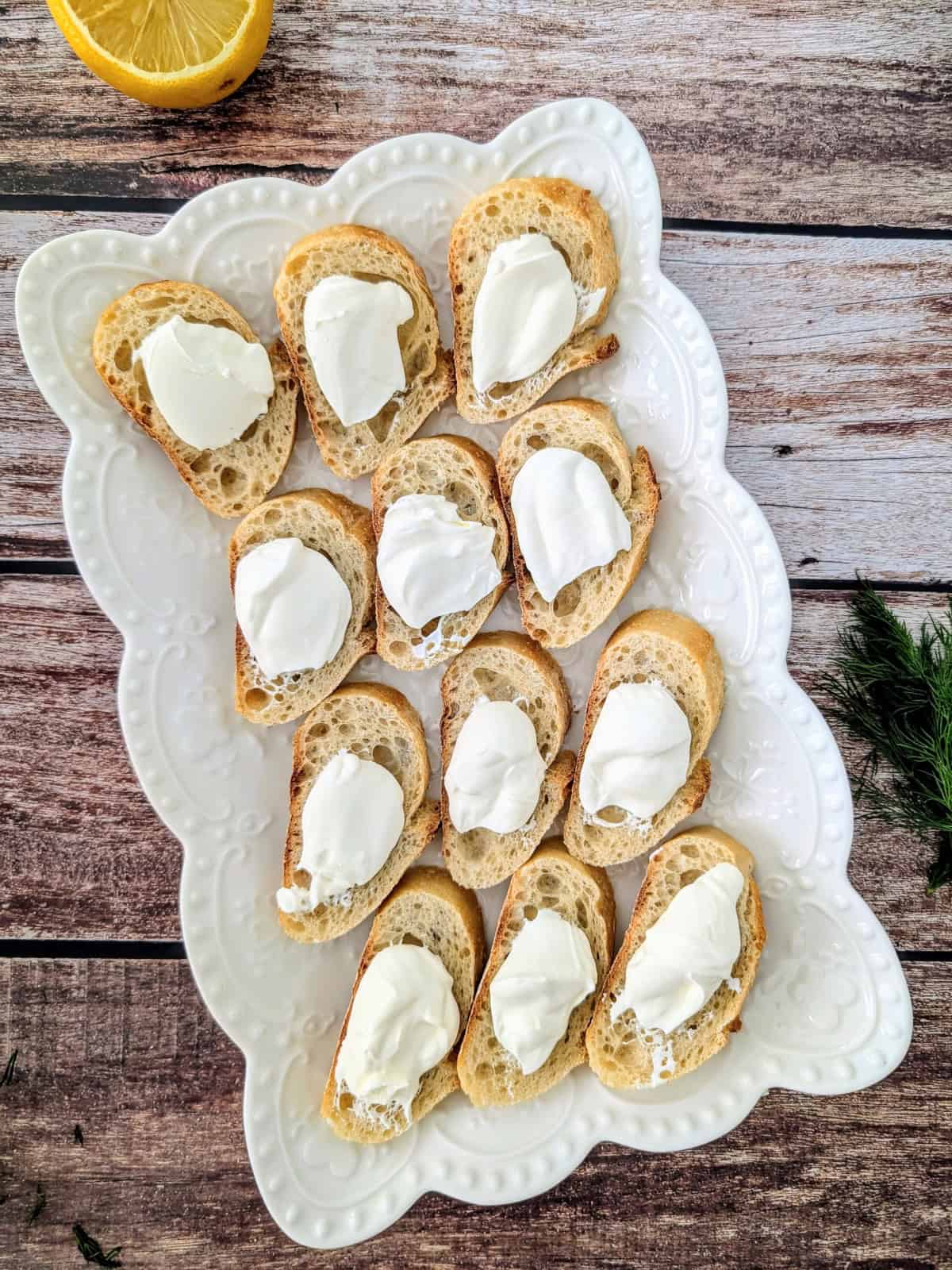 creme fraiche topped over baguette slices on a white platter.