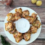 cheesy smashed potatoes with roasted red pepper on large white plate with sour cream dip.
