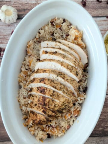 Tender Baked Turkey Breast over rice, in a white serving platter.