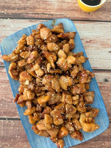 3-ingredient Honey Garlic Chicken on a blue platter sprinkled with sesame seeds.