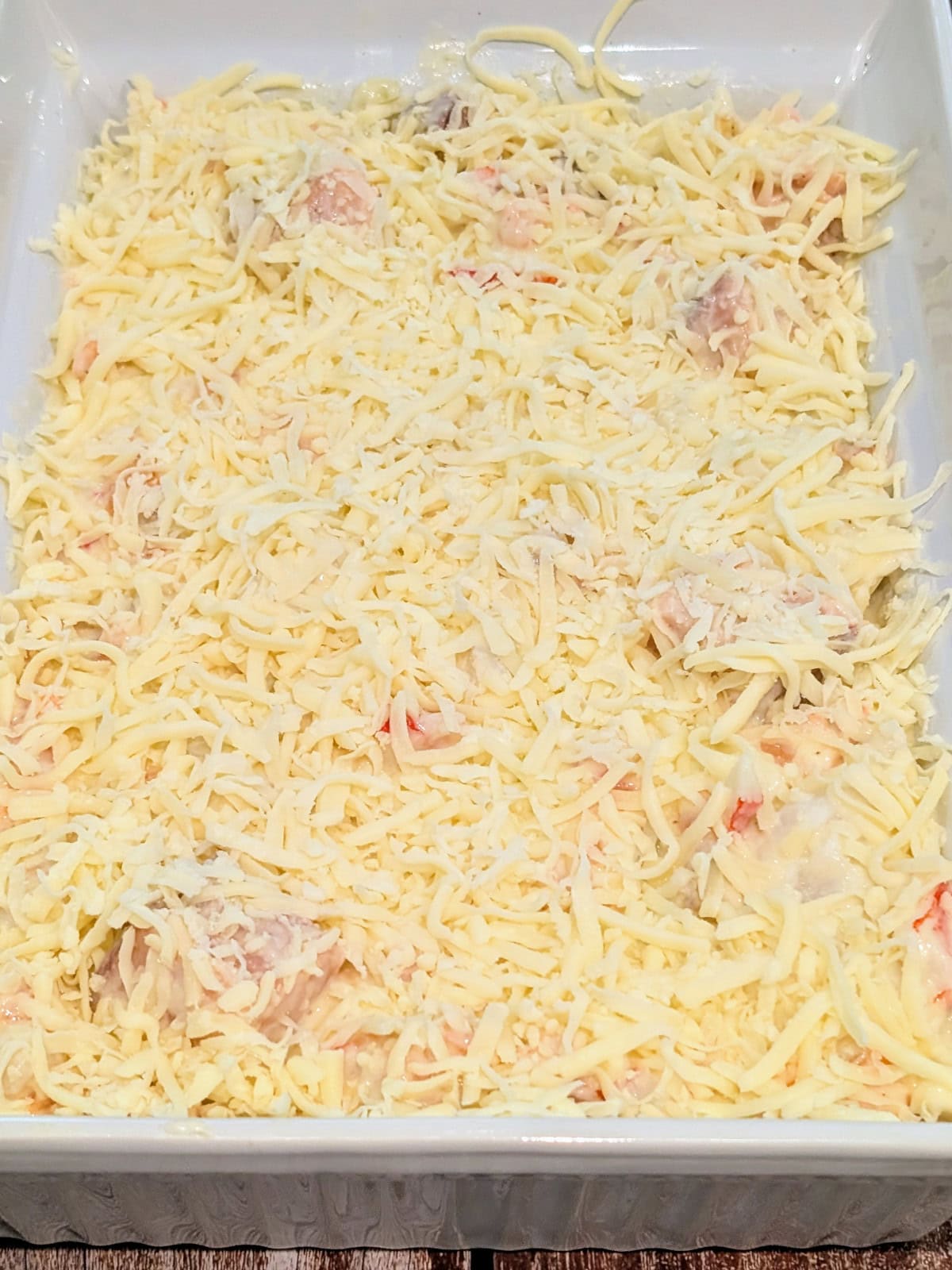 grated cheese spread over seafood layer.