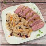 Seared Duck Breast with Cranberry Rice on a white plate.