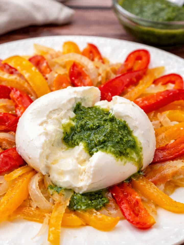 Burrata with Sautéed Peppers and Nut-Free Basil Pesto on a white plate.