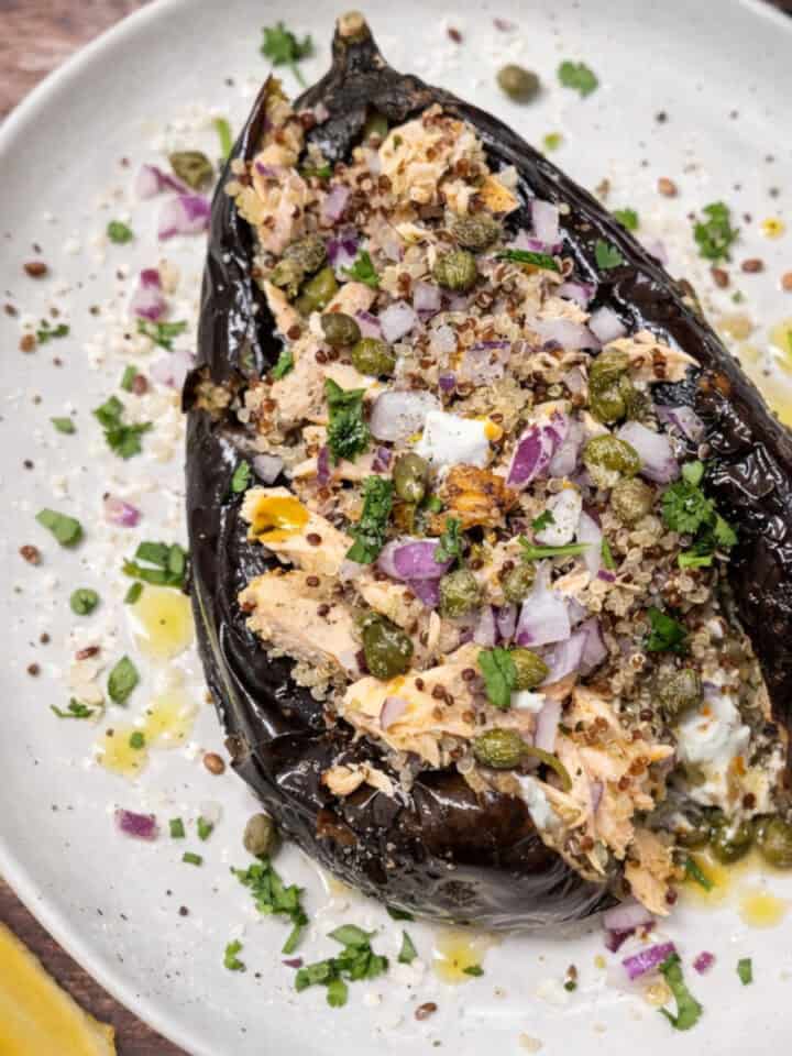 Roasted eggplant bowl filled with quinoa and leftover salmon, topped with capers and fresh herbs.