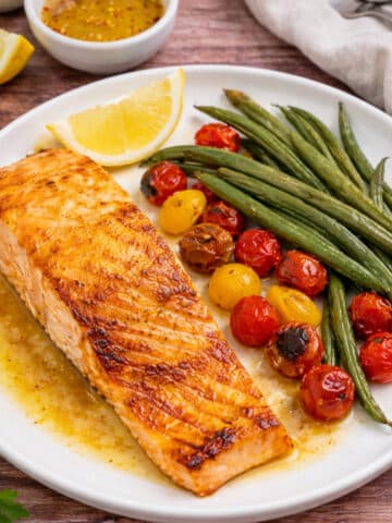Easy healthy lemon Dijon honey baked salmon with green beans and tomatoes.