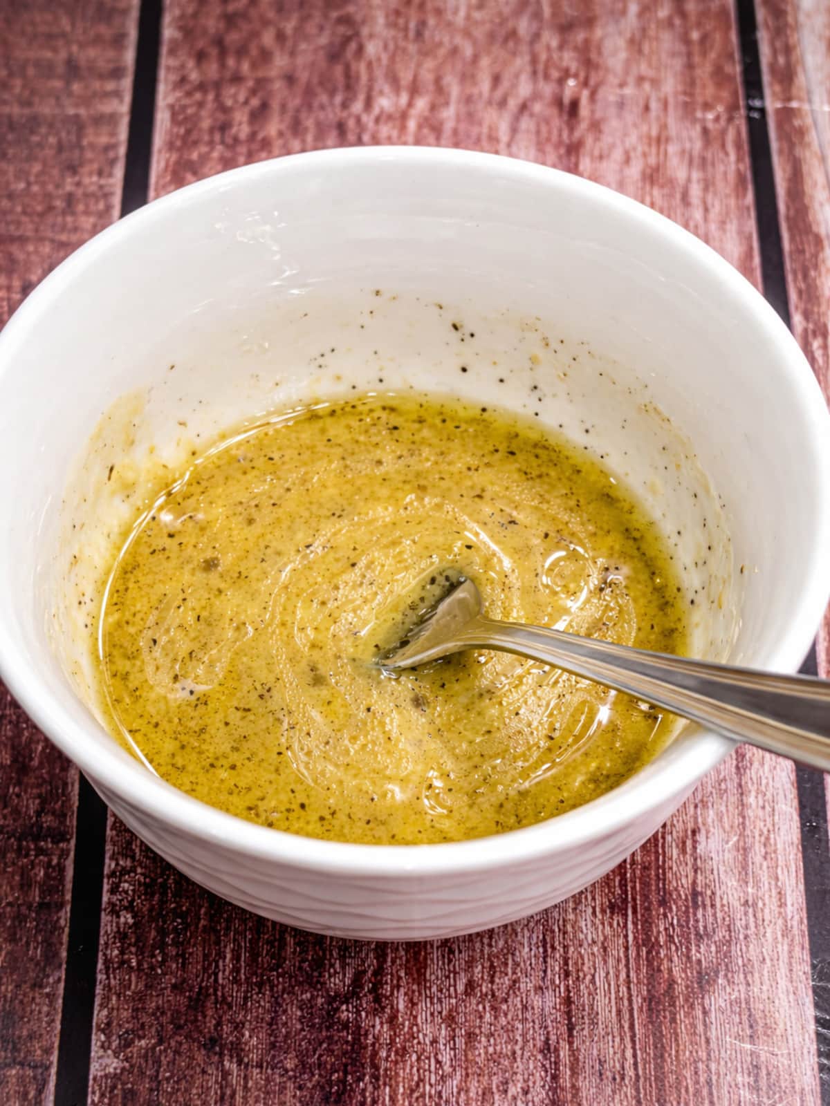 Lemon Dijon honey sauce being mixed in a white bowl for baked salmon.