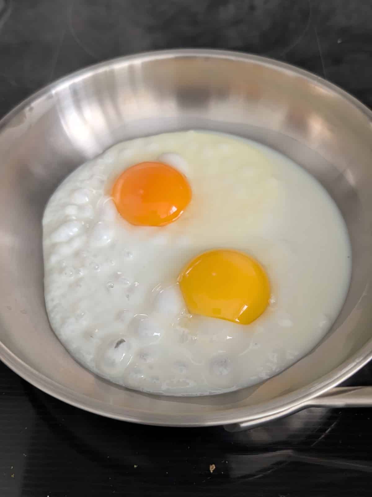 dark egg yolk color and light yellow egg yolk color in eggs cooking in a pan.