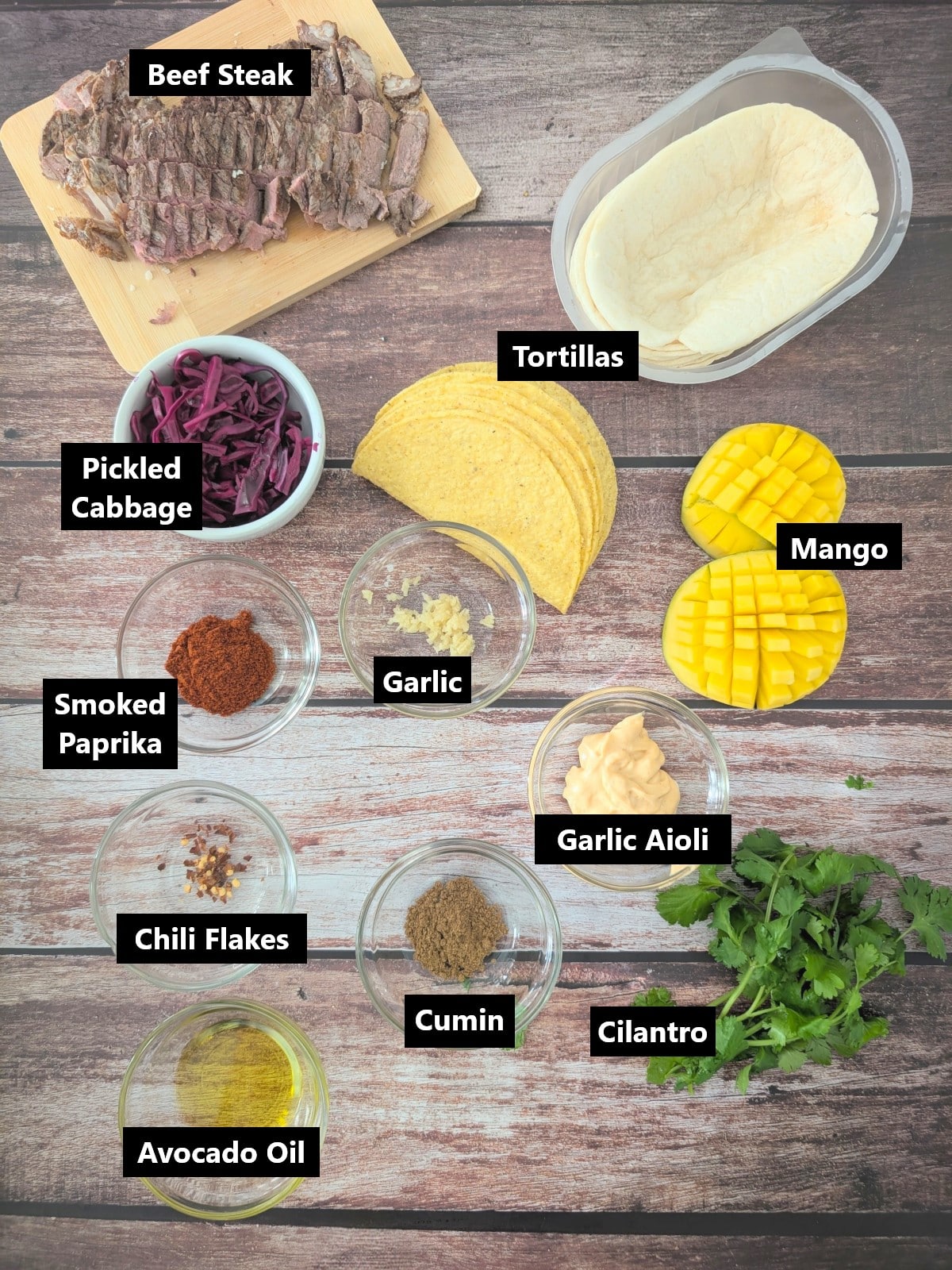 Ingredients for leftover steak tacos including sliced steak, mango, pickled red cabbage, spices and garlic aioli.