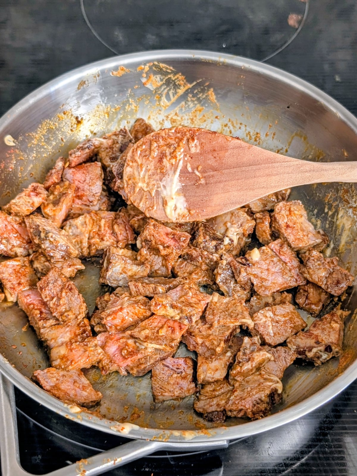 Leftover steak pieces cooking in a skillet with smoked paprika, cumin and garlic aioli.
