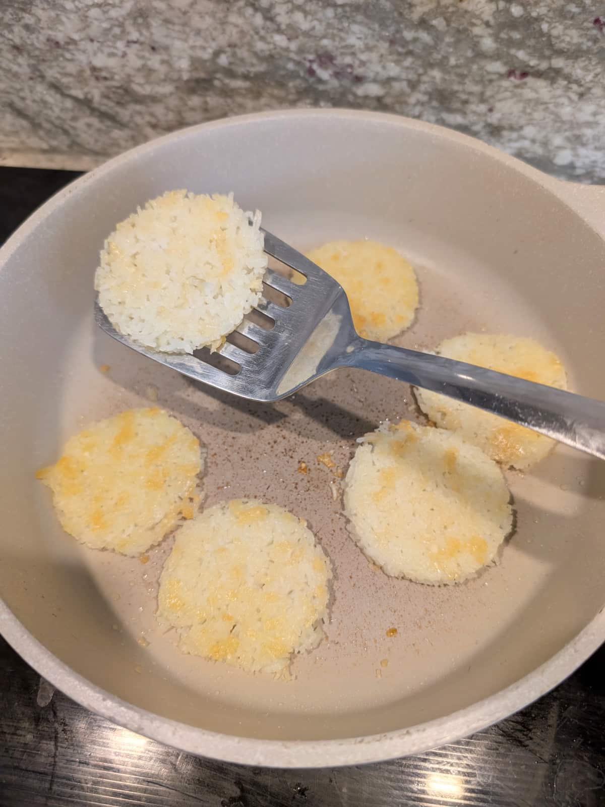 spatula flipping Crispy rice rounds in a pan until golden brown.