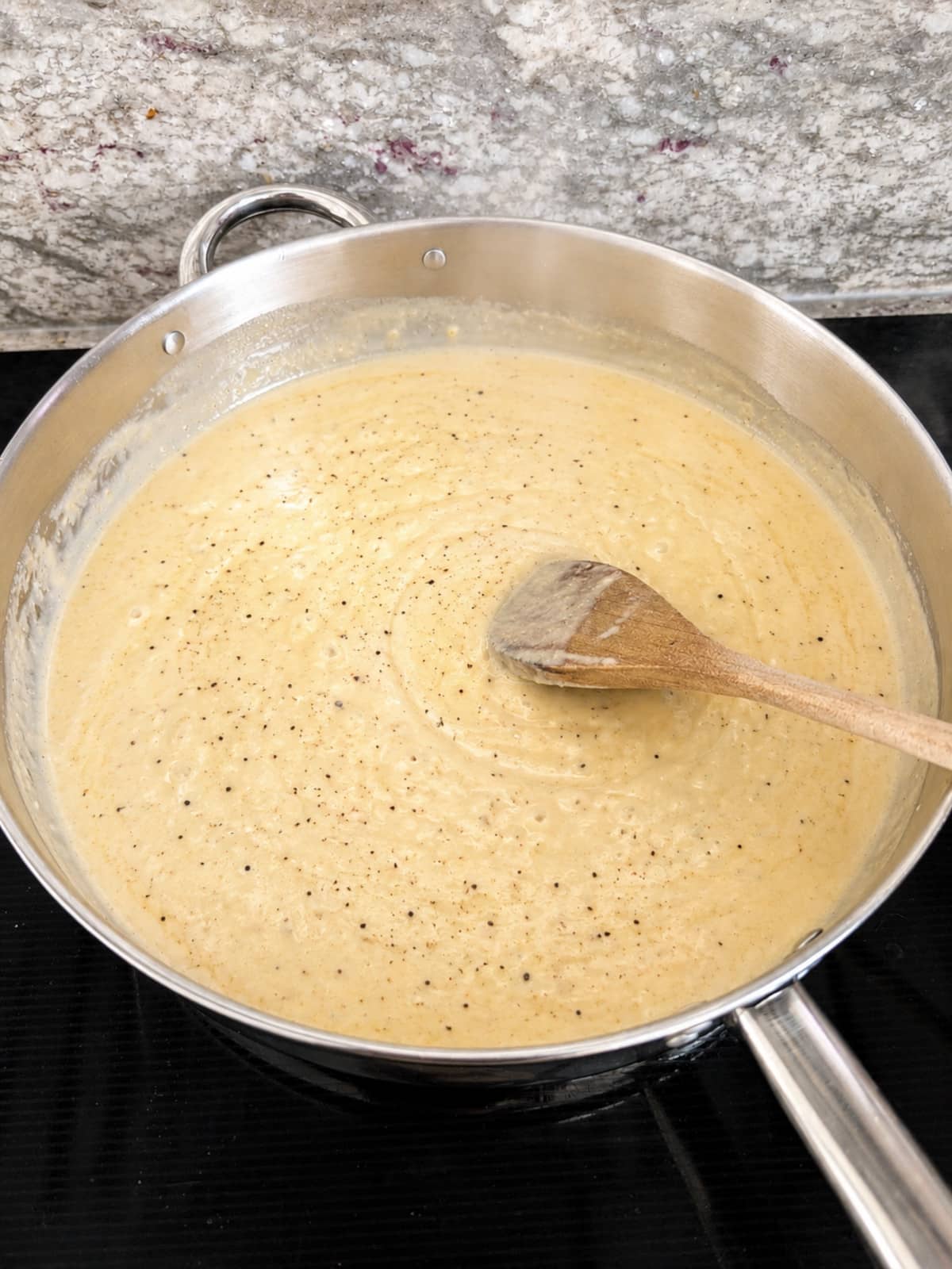 creamy garlic sauce cooking in a pan on the stove.