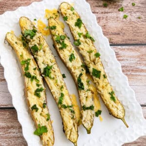 Roasted garlic Parmesan Japanese eggplant topped with fresh cilantro on a white serving platter.