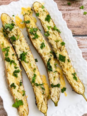 Roasted garlic Parmesan Japanese eggplant topped with fresh cilantro on a white serving platter.