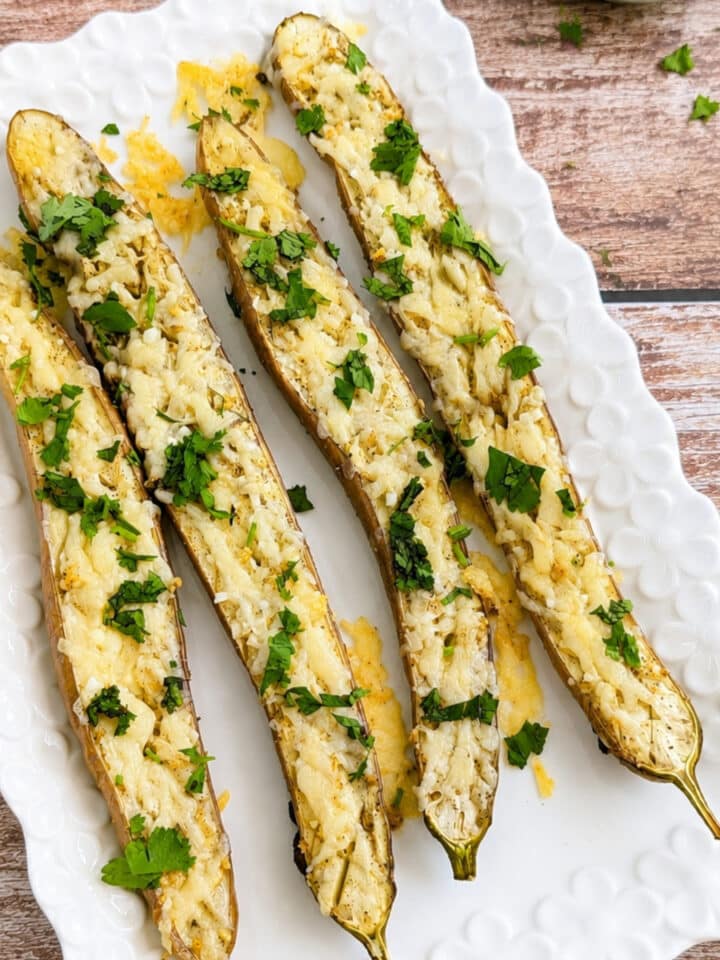 Roasted garlic Parmesan Japanese eggplant topped with fresh cilantro on a white serving platter.