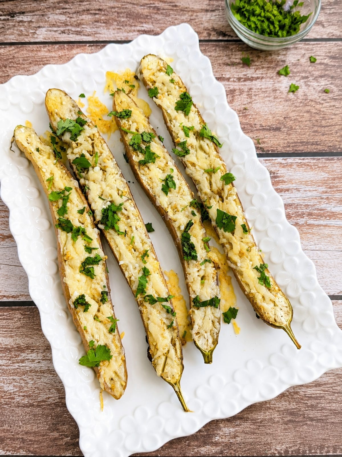 Roasted garlic Parmesan Japanese eggplant topped with fresh cilantro on a white serving platter.