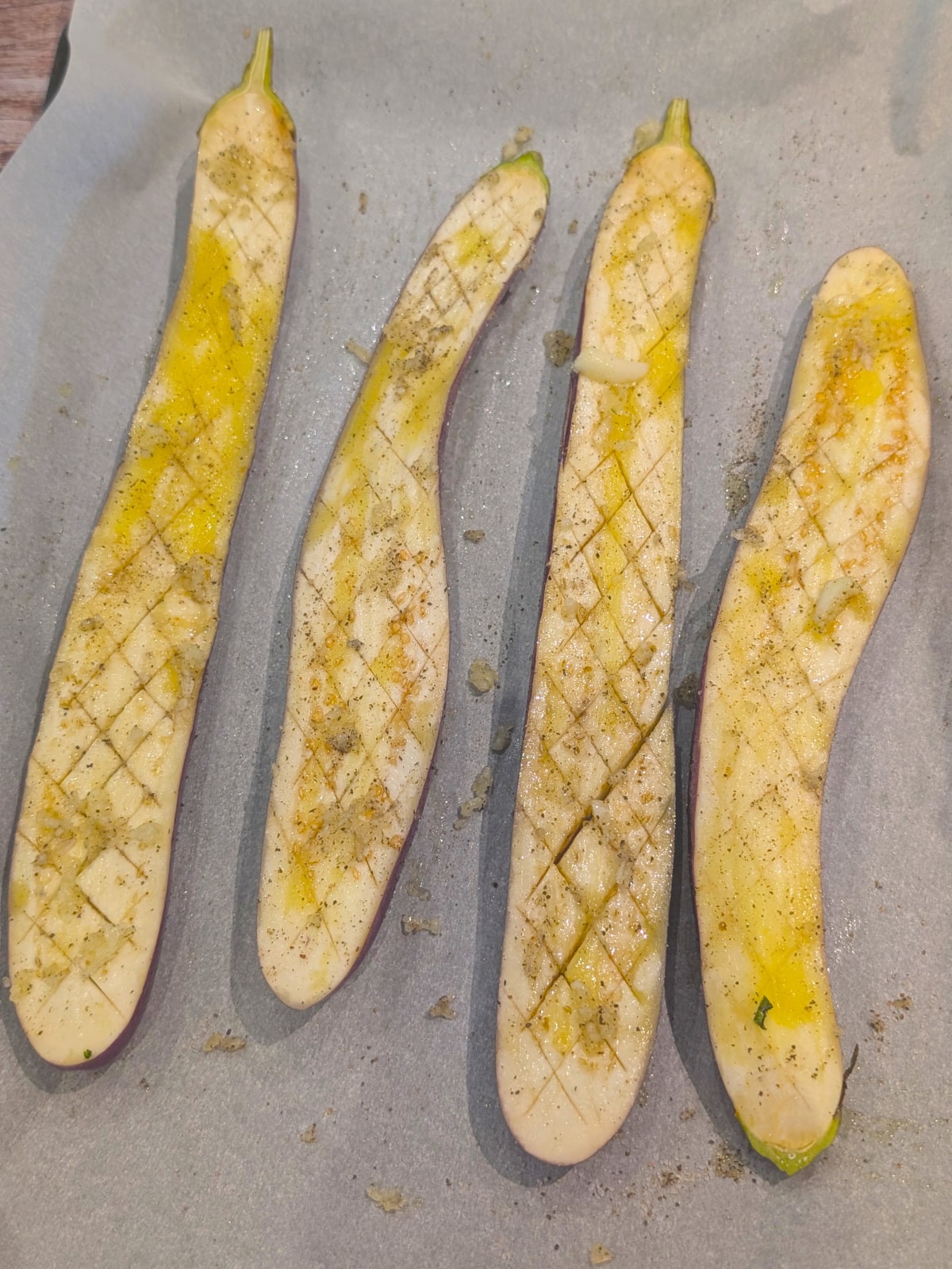 Japanese eggplant halves scored and seasoned with salt, pepper, and freshly minced garlic.